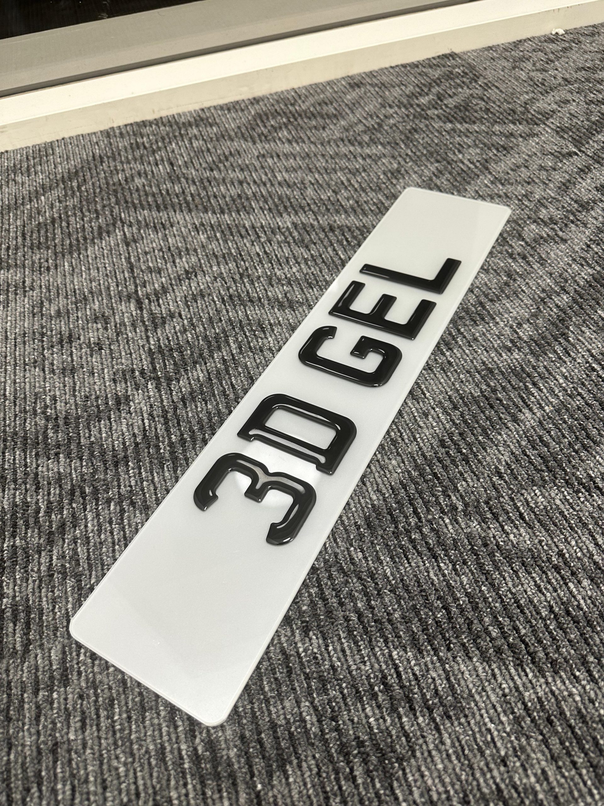 A close-up of a 3D Gel number plate with raised, glossy characters.