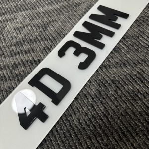 Close-up view of a modern UK vehicle registration plate displaying standard DVLA format with black lettering on white reflective background