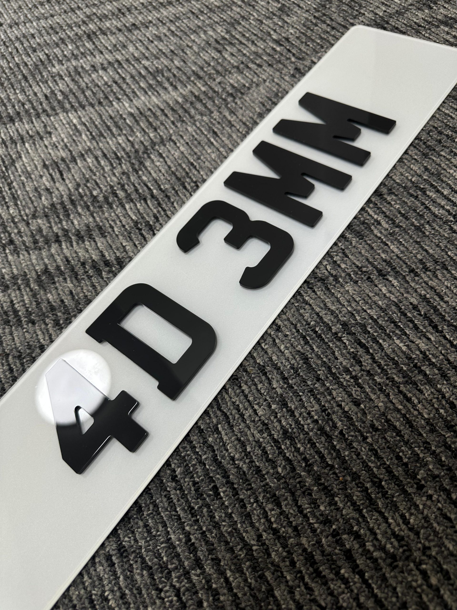 A sharp, laser-cut 4D number plate with deep black characters.